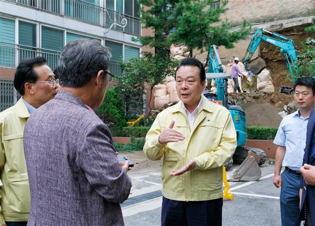 노현송(가운데) 강서구청장이 지난달 22일 화곡동 주택가 석축 붕괴 현장을 찾아 주민 안전을 챙기며, 직원들에게 체계적인 점검과 조치를 당부하고 있다. 강서구 제공