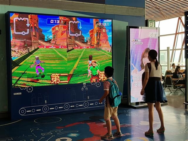 베이징 공항에서 젊은 엄마와 아이가 탑승창구 앞에 설치된 전자 시뮬레이션 기기를 이용해 게임을 하고 있다.