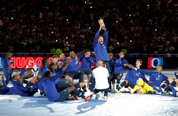 경기장 전체의 조명을 끈 뒤 프랑스 축구대표팀 선수들이 그라운드에 앉아 주장인 유고 요리스가 러시아월드컵 우승 트로피를 들어올리자 환호하고 있다. 파리 로이터 연합뉴스