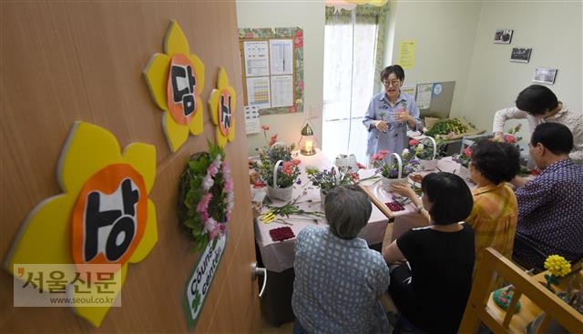서울 성북구 미르사랑데이케어센터에서 진행된 자조모임에서 치매 환자 가족들이 모여 꽃꽂이를 하고 있다. 손덕현(57·가운데) 플라워 심리치료사가 참석자들에게 꽃이 주는 심리적 안정 효과에 대해 설명하고 있다. 박지환 기자 popocar@seoul.co.kr