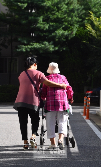 경기도 고양에 사는 임순달(57)씨가 지난 7일 치매에 걸려 거동이 불편한 시어머니를 모시고 산책을 하고 있다. 요양보호사인 임씨는 인근에 사는 치매 노부부에게도 방문요양서비스를 제공하는 등 홀로 세 명의 치매환자를 돌보고 있다. 안주영 기자 jya@seoul.co.kr