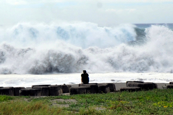 대만의 한 바닷가에 앉은 남성이 14일(현지시간) 슈퍼태풍 망쿳이 만든 파도를 보고 있다.