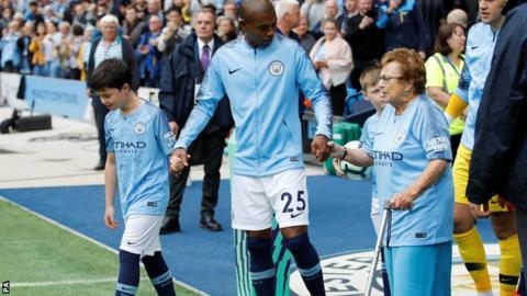 잉글랜드 프로축구 맨시티의 페르난지뉴(가운데)가 97세인 올가 할론 할머니의 손을 이끌어 그라운드로 걸어나오고 있다. 