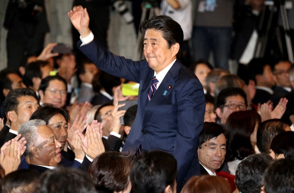 아베 신조 일본 총리가 20일 도쿄 자민당 당사에서 열린 총재선거에서 70%에 가까운 지지율로 압승한 뒤 오른손을 번쩍 들어 박수에 화답하고 있다. 아베 총리는 이날 승리로 총리직 3연임을 확정하면서 일본 최장수 총리 기록에 한층 다가서게 됐다.  도쿄 AP 연합뉴스