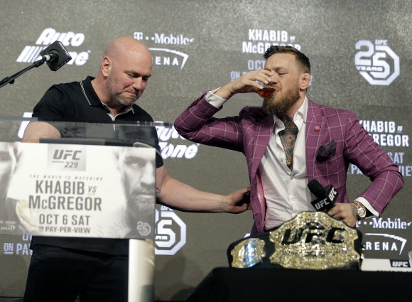 데이나 화이트(왼쪽) UFC 대표가 지켜보는 가운데 코너 맥그리거가 자신의 위스키 제품을 시원하게 들이키고 있다. 뉴욕 AP 연합뉴스 