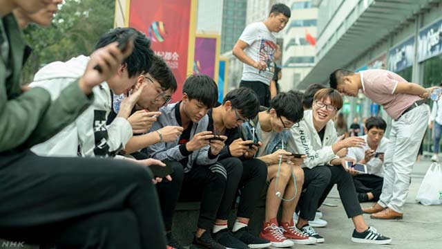 중국 텐진 시내에서 젊은이들이 모여 앉아 담소를 하면서 핸드폰을 이용한 온라인 게임을 즐기고 있다. NHK 웹사이트