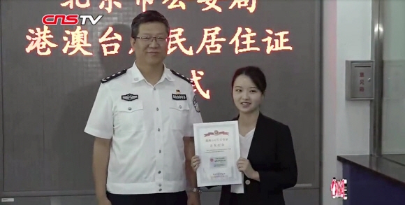 지난 9월7일 베이징 공안국에서 본토 거주증을 취득한 마카오인 린웨이옌(오른쪽)이 거주증을 들어 보여주며 활짝 웃고 있다. 중국신문사TV 캡처 
