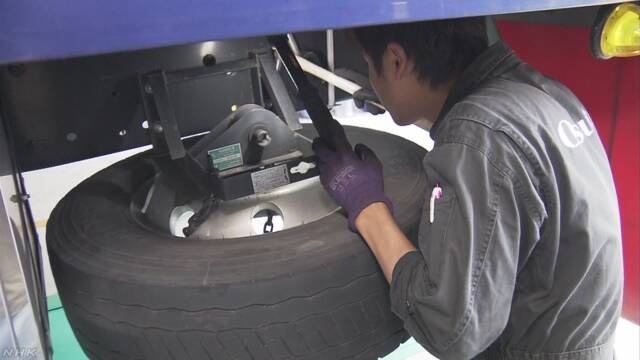 한 정비사가 대형트럭에 부착돼 있는 예비 타이어의 고정 상황을 점검하고 있다. NHK 웹사이트.