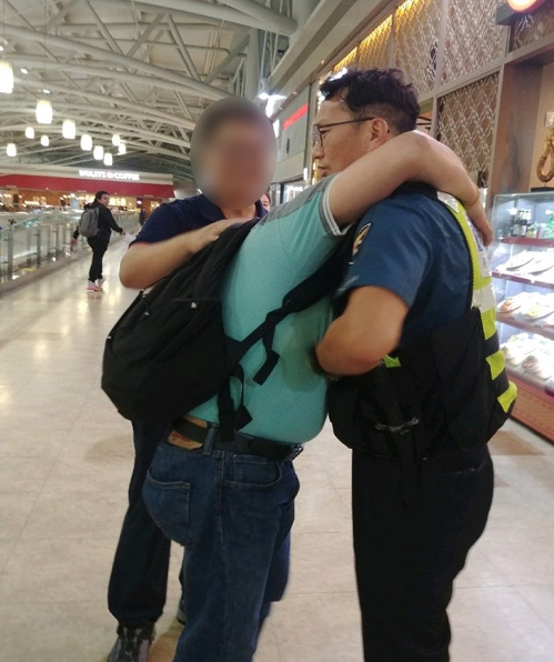 필리핀 외국인 노동자 하타알리씨가 지난 21일 김해공항에서 자신의 가방을 찾아준 경찰관을 끌어안고 감사의 뜻을 전하고 있다. 부산경찰청 제공
