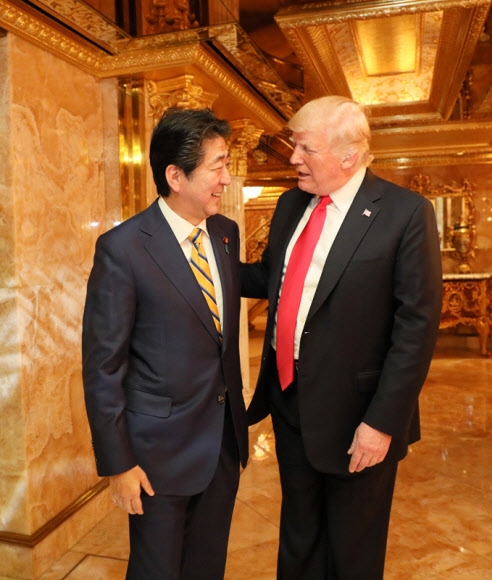 도널드 트럼프(오른쪽) 미국 대통령이 지난 23일(현지시간) 뉴욕 트럼프타워에서 열린 만찬에 참석한 아베 신조 일본 총리를 반갑게 맞이하고 있다.  일본 총리실 제공·연합뉴스