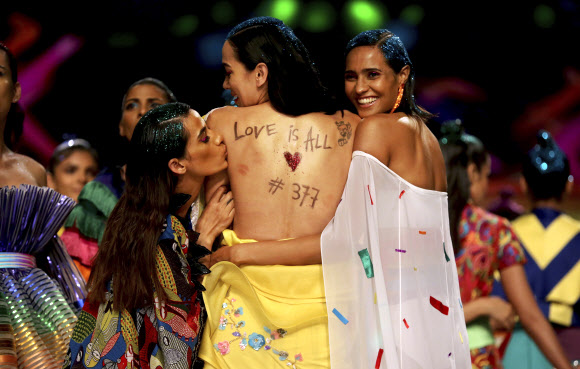 모델이 14일(현지시간) 인도 뉴델리에서 열린 LGBTQ 커뮤니티의 상징인 ‘레인보우’를 테마로 한 ‘Lotus Make-up 인도 패션 위크’ 그랜드 피날레 중 메시지를 쓴 다른 모델의 등에 키스를 하고 있다. AP 연합뉴스