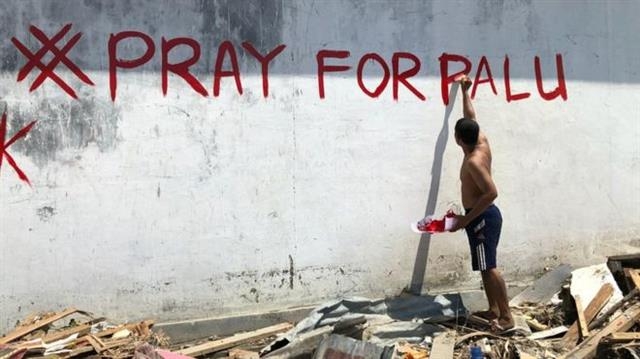 한 남성이 최근 강진과 쓰나미 피해를 입은 인도네시아 팔루를 위해 기도해달라는 문구를 쓰고 있다. BBC 캡처