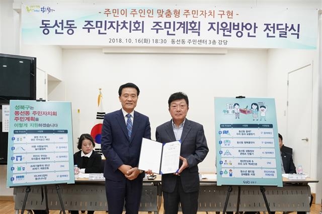 이승로(왼쪽) 성북구청장이 지난 16일 동선동 주민자치회 전례회의에서 유재승(오른쪽) 동선동 주민자치회위원장에게 주민자치계획 지원방안을 전달하고 기념촬영을 하고 있다. 성북구 제공