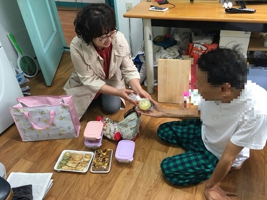 서울 동작구 흑석동 주민이 가사 활동이 어려운 홀몸 어르신 가정을 찾아 계절에 맞는 밑반찬을 권하고 있다. 동작구 제공