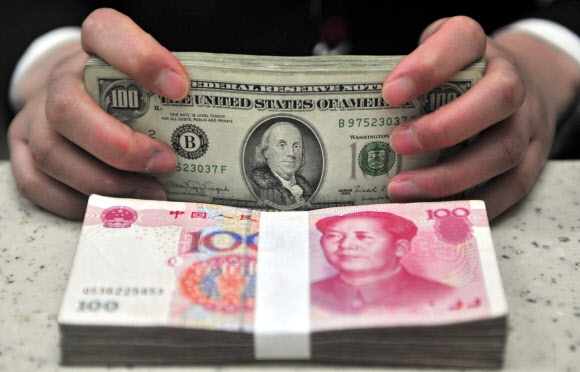 중국의 법정 디지털 화폐인 ‘디지털 위안’이 마침내 베일을 벗었다. 사진은 중국의 한 은행에서 은행원이 달러화와 위안화를 세는 모습. 서울신문 DB