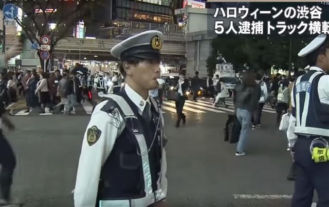 2019년 일본 도쿄 시부야에서 경찰관들이 핼러윈 축제에 참여한 사람들의 행렬을 통제하고 있다. 도쿄 MX TV 화면 캡처