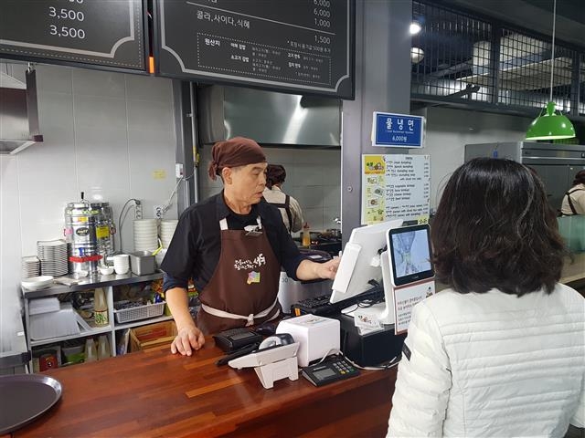 퇴직 후 식음료 분야 경력을 살려 분식점 ‘엄마 손만두 소풍’ 매니저로 취업한 엄기범씨가 주문을 받고 있다.  성동구 제공