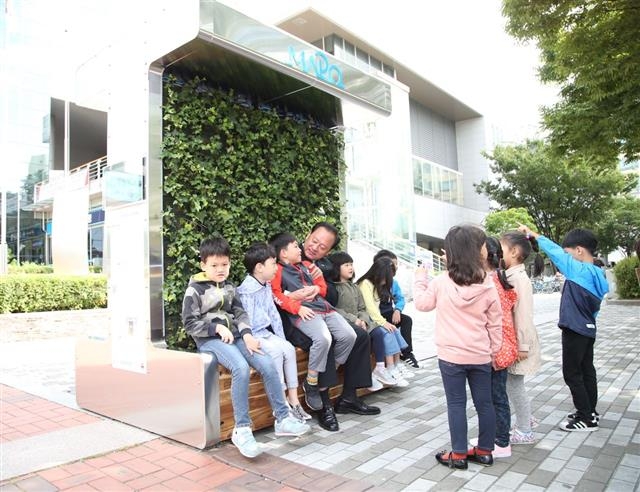 유 구청장이 최근 구청 앞에 시범 설치된 미세먼지 저감 벤치를 보러 온 지역 어린이집 아이들과 놀아주고 있다.  마포구 제공