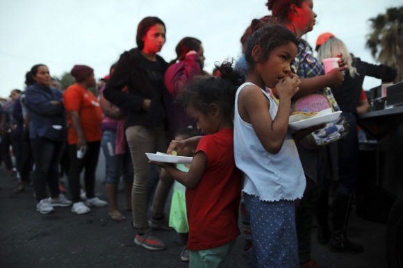 19일(현지시간) 중미 이민자 행렬인 캐러밴에 동참한 여성과 아이들이 미국으로 가기 위해 멕시코에 도착해 줄 서서 차례로 무료 저녁 배식을 받고 있다. 2018.11.20 멕시코 AP 연합뉴스