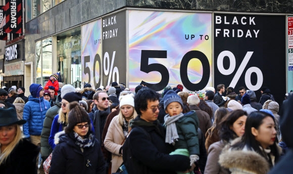 블프를 맞은 지난 23일(현지시간) 뉴욕 맨해튼에서 50% 할인을 내세운 대형 광고판 앞을 지나는 시민들. AP 연합뉴스