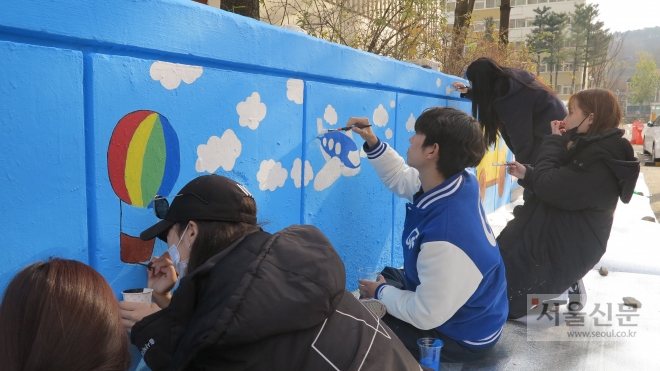 가천대 예술대학 학생들이 25일 성남시에 위치한 임대아파트에서 벽화를 그리며 재능나눔 봉사활동을 펼치고 있다. (가천대 제공) 