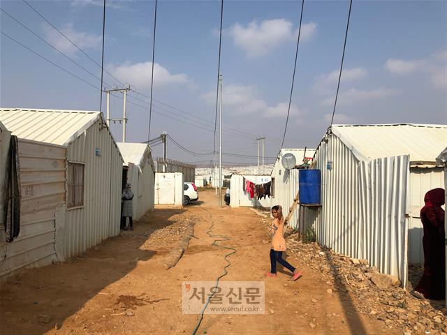 시리아 난민 소녀가 14일 아즈락 난민 캠프 거리를 걷다가 사진을 찍는 기자를 바라보고 있다.