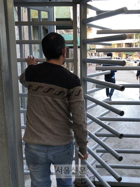 한 팔레스타인 청년이 지난 19일 팔레스타인 자치지역 서안지구 헤브론 내 이스라엘 정착촌 출입구에 설치한 철제 통행 차단기를 지나가고 있다. 헤브론에 주둔한 이스라엘군은 유사시 이 문을 폐쇄한다.
