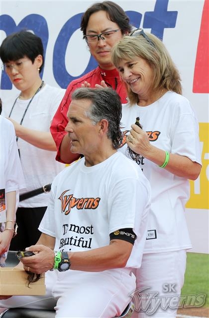 힐만 SK 감독(왼쪽)의 아내 매리가 지난 8월 11일 인천 SK행복드림구장에서 열린 KIA와의 경기에 앞서 남편이 약 1년간 기른 머리카락을 자르고 있다. SK 제공