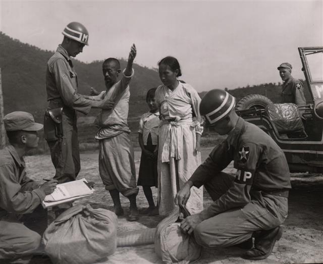 1951년 7월 피난민으로 보이는 민간인 가족이 포로수용소에 수용되기에 앞서 신체 수색을 받고 있는 모습.  대한민국역사박물관 제공