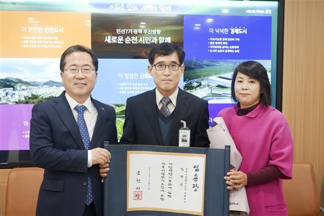 교지 형태의 승진 임명장을 김면균 체육시설관리소장에게 수여한 뒤 이들 부부와 기념사진을 찍고 있는 허 시장.  순천시 제공