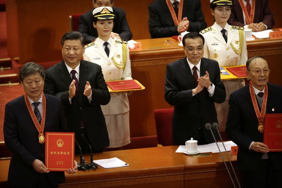 시진핑(뒷줄 왼쪽) 중국 국가주석이 18일 베이징 인민대회당에서 열린 ‘개혁개방 40주년 경축 대회’에서 리커창(오른쪽) 총리와 함께 이날 유공자 표창을 받은 인사들을 축하하며 박수를 치고 있다. 중국 발전에 기여한 공로를 인정받은 수상자들은 메달을 목에 걸고 ‘중국 개혁개방 선봉 증서’라는 글이 적힌 빨간색 표지의 상장을 내보였다. 시 주석은 이날 1시간 반 동안 연설을 통해 “공산당의 지도 아래 사회주의 현대화 강국 건설과 중국몽 실현” 의지를 강조하면서 미국을 의식한 듯 “패권을 추구하지 않겠다”고 밝혔다. 베이징 AFP 연합뉴스