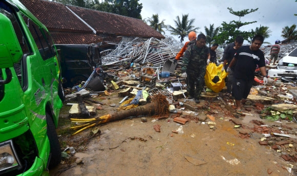 지난 22일 밤 인도네시아 순다해협 일대를 강타한 쓰나미로 23일 현재 222명이 숨진 가운데 20m 높이의 해일이 덮친 카리타의 한 마을에서 구조대가 붕괴된 가옥 더미에서 발견한 사망자를 옮기고 있다.  카리타(인도네시아) AFP 연합뉴스