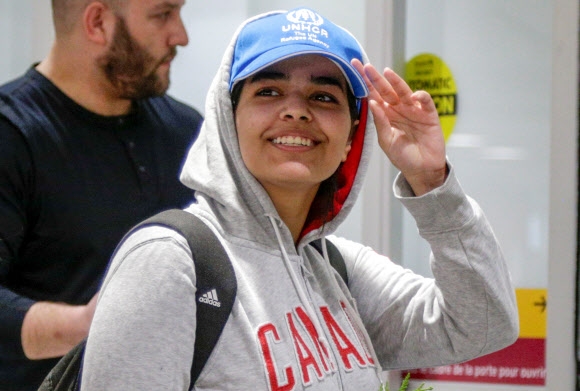 가정 학대를 피해 탈출한 사우디아라비아 소녀 라하프 무함마드 알쿠눈이 12일(현지시간) ‘캐나다’라는 글씨가 새겨진 후드티와 ‘유엔난민기구’(UNHCR) 로고가 박힌 모자 차림으로 캐나다 토론토 피어슨 국제공항에 도착해 환하게 웃고 있다. 토론토 로이터 연합뉴스