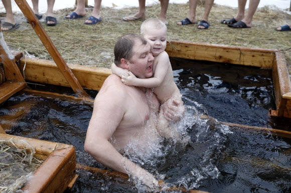19일(현지시간) 러시아에서 한 남성이 아이와 함께 공현 대축일을 맞아 오스탄킨스키 연못에 몸을 담그고 있다. 타스 연합뉴스