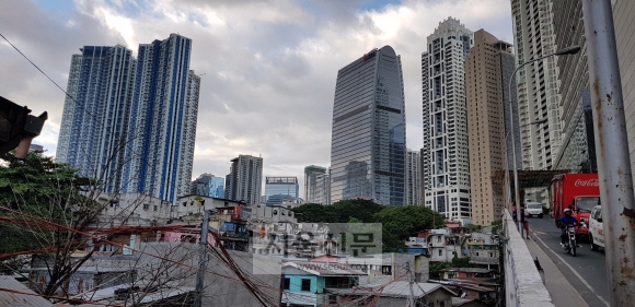 필리핀 수도 마닐라의 ‘강남’으로 떠오른 보니파시오 지역에서 지난 23일 솟아오른 초고층 호화 주택 및 사무용 건물들이 철거를 기다리는 주변 달동네 주택들과 묘한 대조를 이루고 있다. 두테르테 정부의 ‘인프라 우선 정책’이 건설업을 뜨겁게 달구고 있다.