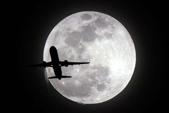 지난달 21일 미국 캘리포니아주 로스엔젤래스 밤 하늘에 뜬 ‘슈퍼문’을 배경으로 비행기가 날아가고 있다. 로스앤젤레스 신화 연합뉴스
