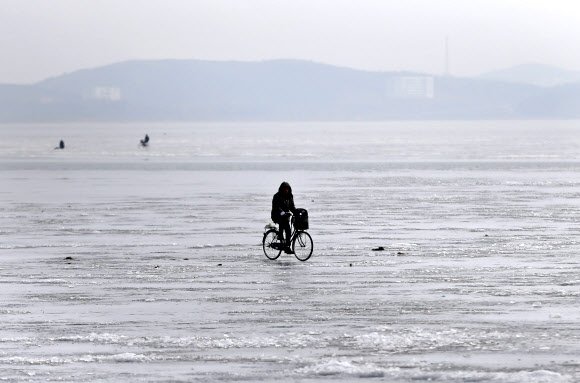 자전거 타고 얼어붙은 대동강 건너는 북한 주민