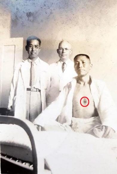 1938년 창사 샹야의원에서 총상에서 회복된 김구(오른쪽)가 의료진과 함께 찍은 사진. 그의 가슴 가운데에 총탄 자국(원)이 선명하다.  부산시립박물관 제공