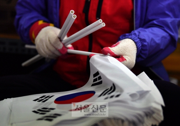 서울 성동구 동영산업 공장에서 한 직원이 손 태극기에 깃대를 넣는 작업을 하고 있다.