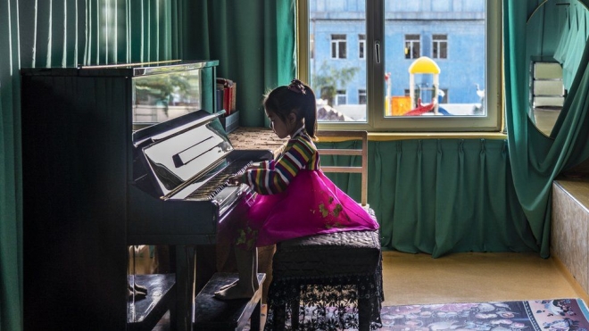 청진 청남유치원에서 한복 차림으로 피아노 연주에 열중하는 소녀.