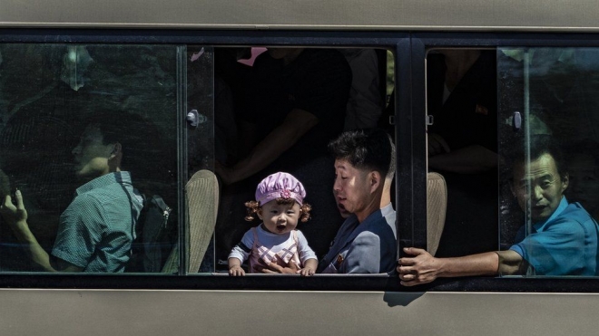 평양 버스 안의 아빠 무릎 위에서 창 밖 세상을 궁금해 하는 어린이.