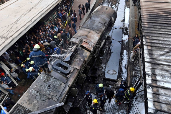 이집트 소방대원들이 27일(현지시간) 카이로 람세스 기차역에서 충돌한 뒤 화재로 전소된 열차에 물을 뿌리고 있다.  카이로 AFP 연합뉴스