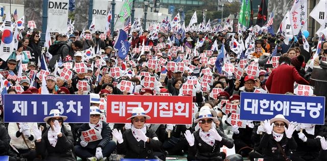 박근혜 전 대통령 탄핵 2년을 맞은 10일 오후 서울역 광장에서 열린 ‘제113차 태극기 집회’에서 박근혜대통령 무죄 석방 1천만 국민운동본부와 대한애국당 등 참석자들이 손팻말과 태극기를 들고 구호를 외치고 있다. 뉴스1