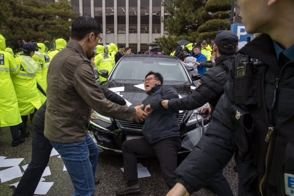 재판을 마치고 광주지방법원을 빠져나가려는 전씨가 탑승한 차량을 한 시민이 몸을 던져 막아서고 있다.  광주 정연호 기자 tpgod@seoul.co.kr