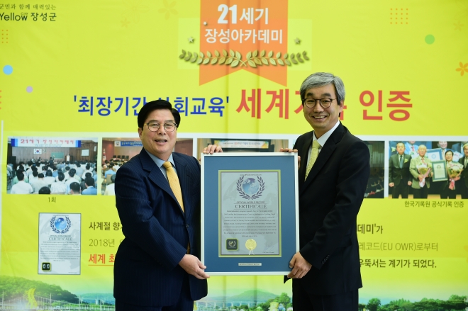 유두석(왼쪽) 장성군수가 김덕은 한국기록원장으로 부터 세계 최장기간 사회교육 강좌 기록 인증패를 받고 있다. 