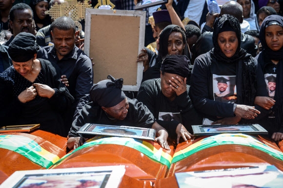 지난 10일 추락해 157명의 목숨을 앗아간 에티오피아항공 소속 보잉 737맥스8 여객기 희생자 유족들이 17일(현지시간) 에티오피아 아디스아바바 트리니티 대성당에서 열린 합동 장례식에서 희생자들의 시신이 담긴 관과 영정 사진을 보며 눈물을 흘리고 있다. 아디스아바바 AFP 연합뉴스
