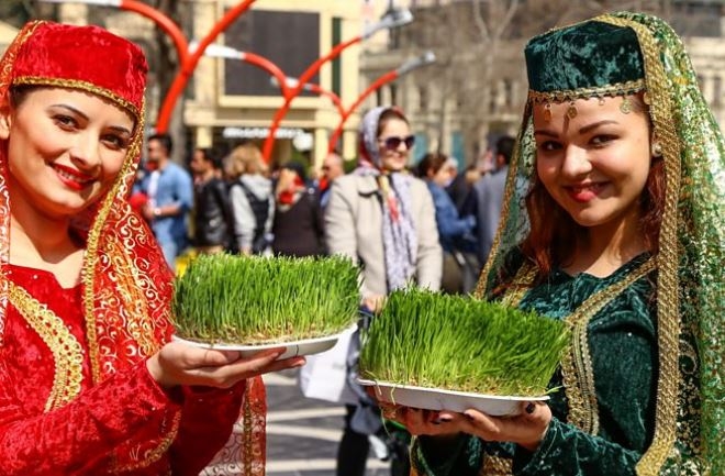 페르시아 전통 의상을 차려 입은 여성들이 새해 첫날인 노루즈 축제를 집안에서 즐길 때 장식하는 새싹 채소 사브제를 들고 미소 짓고 있다. BBC 동영상 캡처