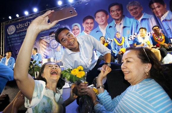 태국 유력 야당의 하나인 민주당의 총리 후보인 아빗시 베자이바 가 지난 18일 방콕의 한 유세장에서 유세 도중 지지자들과 손을 맞잡은 채 사진을 찍으면서 미소를 짓고 있다.      2018. 3. 18.  AP 연합뉴스