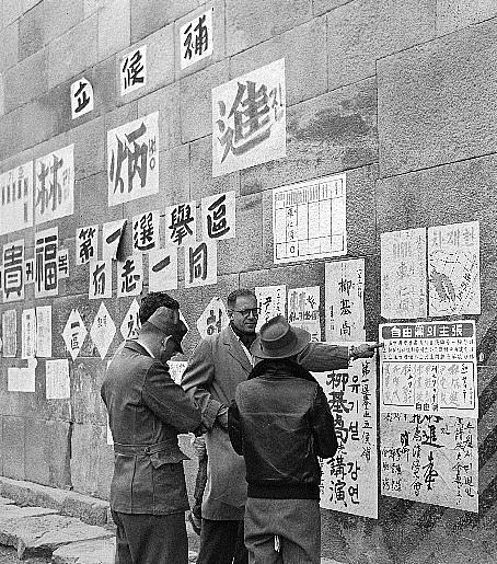 이승만 정부는 전시체제이던 1952년 5월 지방의회의원 선거를 강행했는데, 외국인과 군인 등이 선거벽보를 보며 대화하고 있다.  중앙선거관리위원회 제공