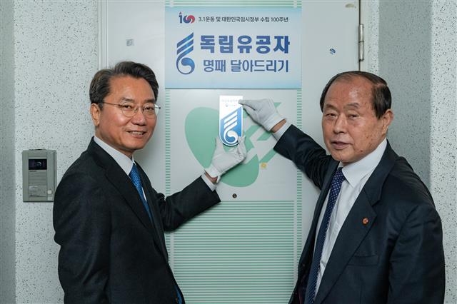 김선갑(왼쪽) 서울 광진구청장이 8일 구의3동에 있는 독립유공자 유족 조상묵씨 자택 현관문에 독립유공자 명패를 달아주고 있다. 광진구 제공